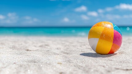 Obraz premium Beach Ball on Sandy Shore with Turquoise Ocean and Summer Sky
