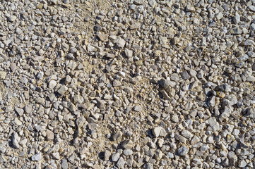 Different sized beige limestone gravel, stones on road background