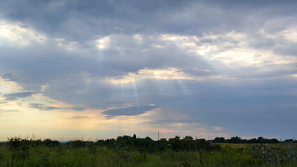 cloudy colorful clouds with sun rays over the rural landscape