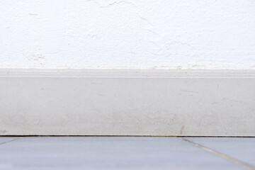 Wall baseboard between blurred floor and white wall texture background. Front view of wall and...