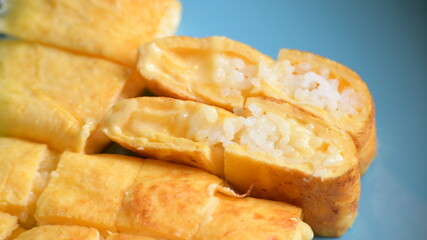 roll omelette stuffed with chesse and rice on blue plate, delicious food in the morning