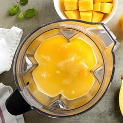 Making smoothie with frozen mango and honey, blender top view
