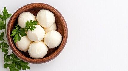 Fresh mozzarella cheese balls in a wooden bowl garnished with parsley leaves on white background