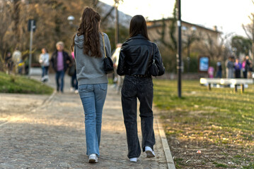 Two young women walk in the park.