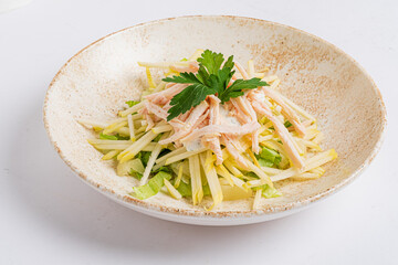 A colorful salad with shredded chicken, crisp greens, and sliced veggies, topped with parsley