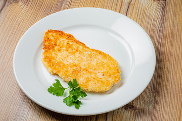 Golden brown cutlet on a sleek plate, enhanced by vibrant green herbs for a fresh touch