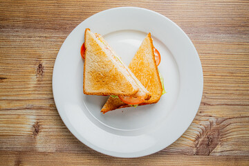 Two triangles of a crispy toasted sandwich filled with savory ingredients and fresh tomatoes