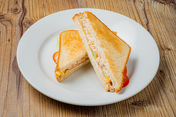 Crispy toasted sandwich cut in half, revealing colorful filling and accompanied by fresh tomatoes