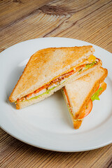 A colorful veggie sandwich with fresh lettuce and tomato sits invitingly on a white plate