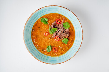 Bowl filled with a hearty stew featuring tender meat, vibrant herbs, and spicy chili slices