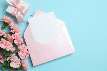 Beautiful bouquet of pink carnations with gift box and paper envelope on a colored background