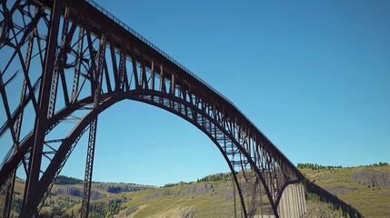 A striking bridge captured from a low perspective, its steel arches stretching upwards against a clear blue sky, symbolizing structural engineering excellence. 