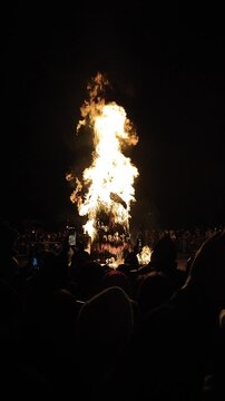 Burning of large straw effigy Winter on square on street during Maslenitsa holiday. Pagan ritual. Lots of people spectating around. Festivities festival outdoors. Vertical