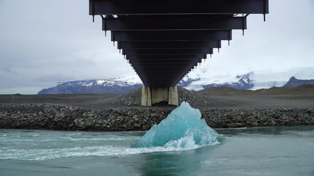 Slow motion of a melting ice block drifts through Jokulsarlon glacier lagoon, Iceland, toward the ocean. A striking reminder of climate change and the impact of global warming.
