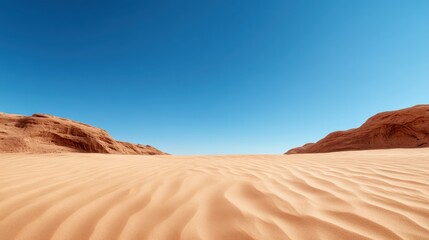 A stunning expanse of golden sand creates a vast desert landscape, emphasized by a clear blue sky that captures the isolation and beauty of this arid environment.