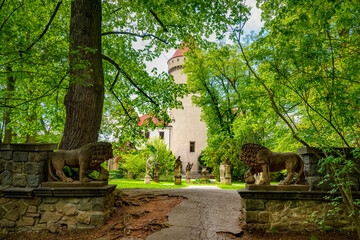 Obraz premium Pathway with lion statues guarding the entrance to Konopiste Castle, surrounded by lush greenery and statues in Benesov, Czech Republic, creates a majestic and historical scene