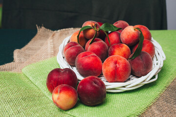 Ripe peaches lie on the table in a white basket