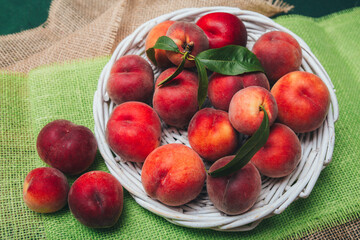 Freshly picked velvet peaches on table in wicker bowl with copy space