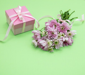 Fresh pink flower bouquet and gift box on pastel green, closeup. Women, mothers day