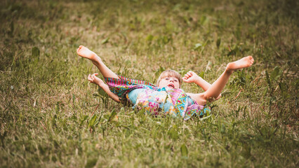 Kind kugelt in der Wiese herum