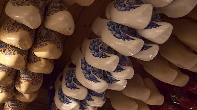 Low angle closeup of Painted Dutch wooden shoes hang from the ceiling in a local shop