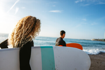 Young people having fun, enjoying their vacations outdoors at the beach with surfboards