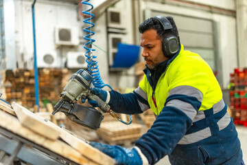 Man using compressed air gun to arrange a pallet in a recycling plant