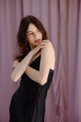 An elegant woman in a black dress on a pink background. Girl spring Young girl