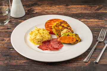 Rustic breakfast plate with fried eggs, grilled vegetables, and turkey bacon