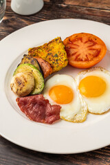 Rustic breakfast plate with fried eggs, grilled vegetables, and turkey bacon