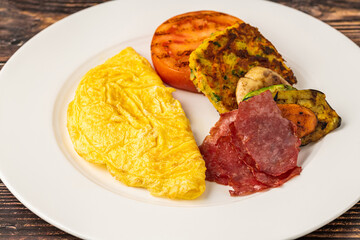 Rustic breakfast plate with fried eggs, grilled vegetables, and turkey bacon