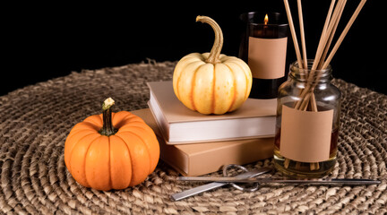 two small pumpkins and a burning candle on a stack of books