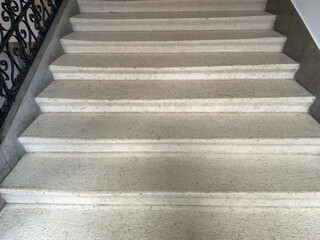 Close-up view of a well-crafted stone staircase featuring clean lines and a textured surface, bordered by a decorative wrought iron railing. 