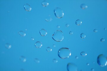 Bright and glossy blue water drops scattered across a smooth surface, creating a refreshing and dynamic visual effect, perfect for backgrounds, designs, and creative projects.

