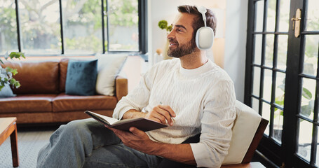 Home, man and thinking with headphones for notebook, writing thoughts and personal reflection with...