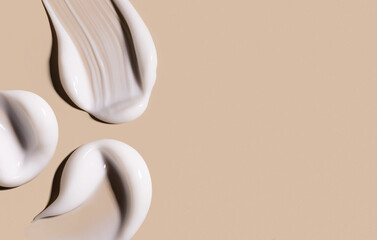 creamy texture of cosmetic samples on a pastel beige background