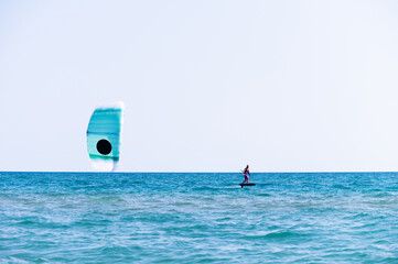 Naklejka premium woman at sea rides a hydrofoil surfboard using a kite wing. Extreme sport, fast travel across the sea on a board