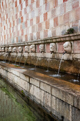 Closeup of the square of the fountain of the 99 spouts (In Italian: Fontana delle 99 cannelle) located in the historic center of L'Aquila, in Abruzzo, Italy. It's a monumental fountain.