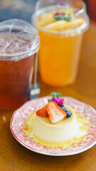 A beautifully presented panna cotta topped with fresh berries, served alongside refreshing iced beverages in a vibrant setting.