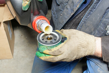 The auto mechanic fills the filter with oil before installing it on the engine.