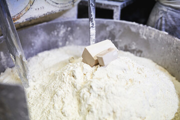Fresh yeast on flour mound in industrial mixing machine at bakery