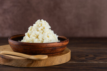Unrefined raw shea butter in a clay bowl on a wooden board and table. Vegan food. Copy space.