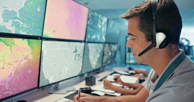 Computer, screen and man with headset in control room for storm tracking, satellite forecast or writing weather pattern. Meteorology, person and radar display for atmosphere monitor or cyclone data