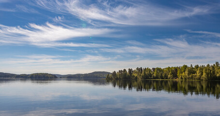A beautiful lake with a clear blue sky and trees in the background