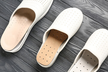 Leather slippers with orthopedic insoles on dark wooden background, closeup
