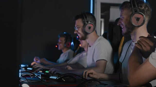 Round victory, cyber team celebrates rejoices map win, E sport championship at gaming club. Happy emotions. Adult Pro gamers play shooter video game on desktop at LAN cafe. Real time strategy on PC