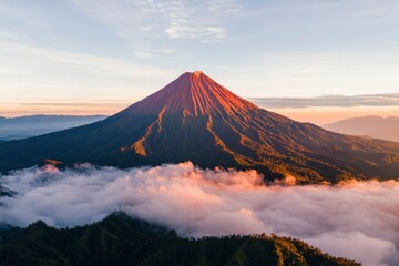 Fototapeta premium Volcano peak over clouds at sunrise. Scenic landscape with a volcano and forest