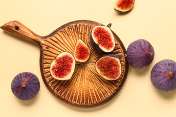 Wooden board with cut fresh figs on yellow background