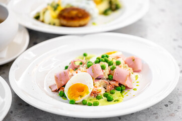 Sliced ham, soft-boiled egg, green peas, and creamy vegetable salad served on a white plate. Minimalist composition, vibrant colors, perfect for food photography or culinary content.