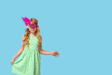 Funny little girl wearing carnival mask on blue background